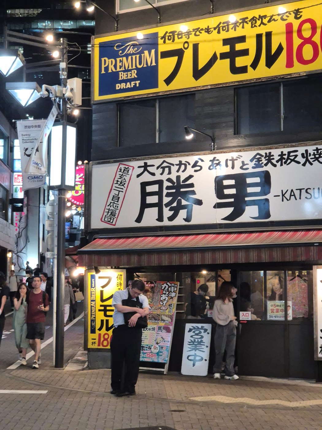 Man with a bag in front of an izakaya at night, Shibuya