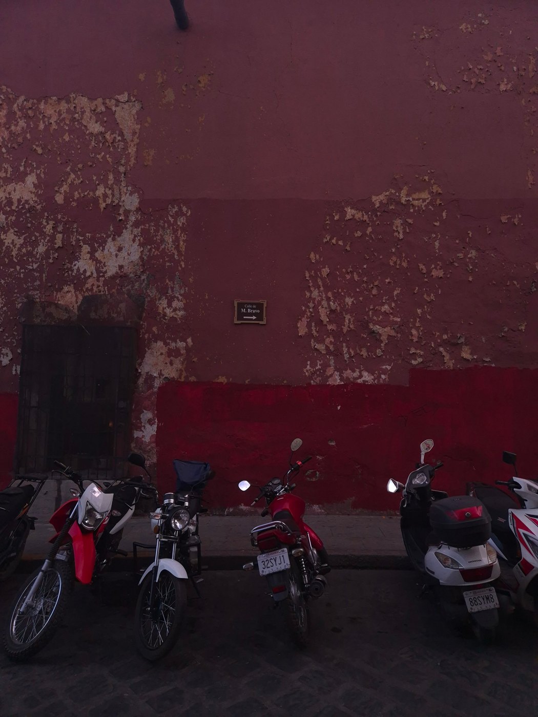 Motorcycles against a peeling red wall, Oaxaca