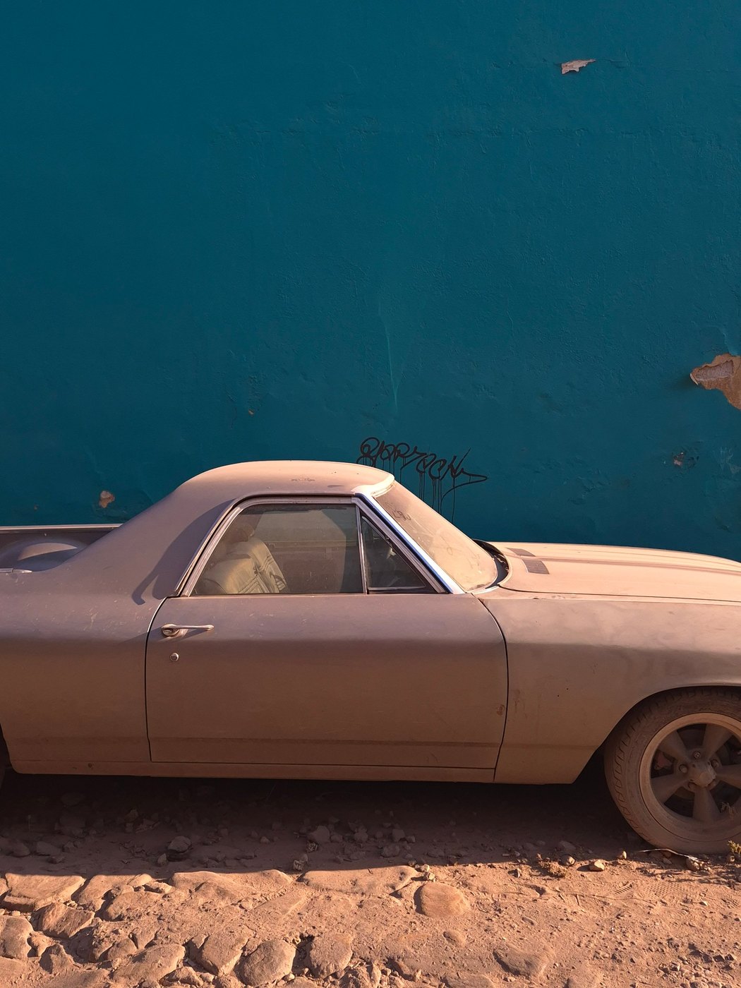 Dusty pickup truck against a teal wall