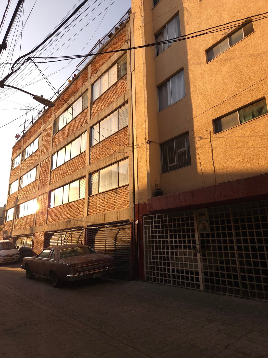 Brick building and parked car at sunset, Mexico City