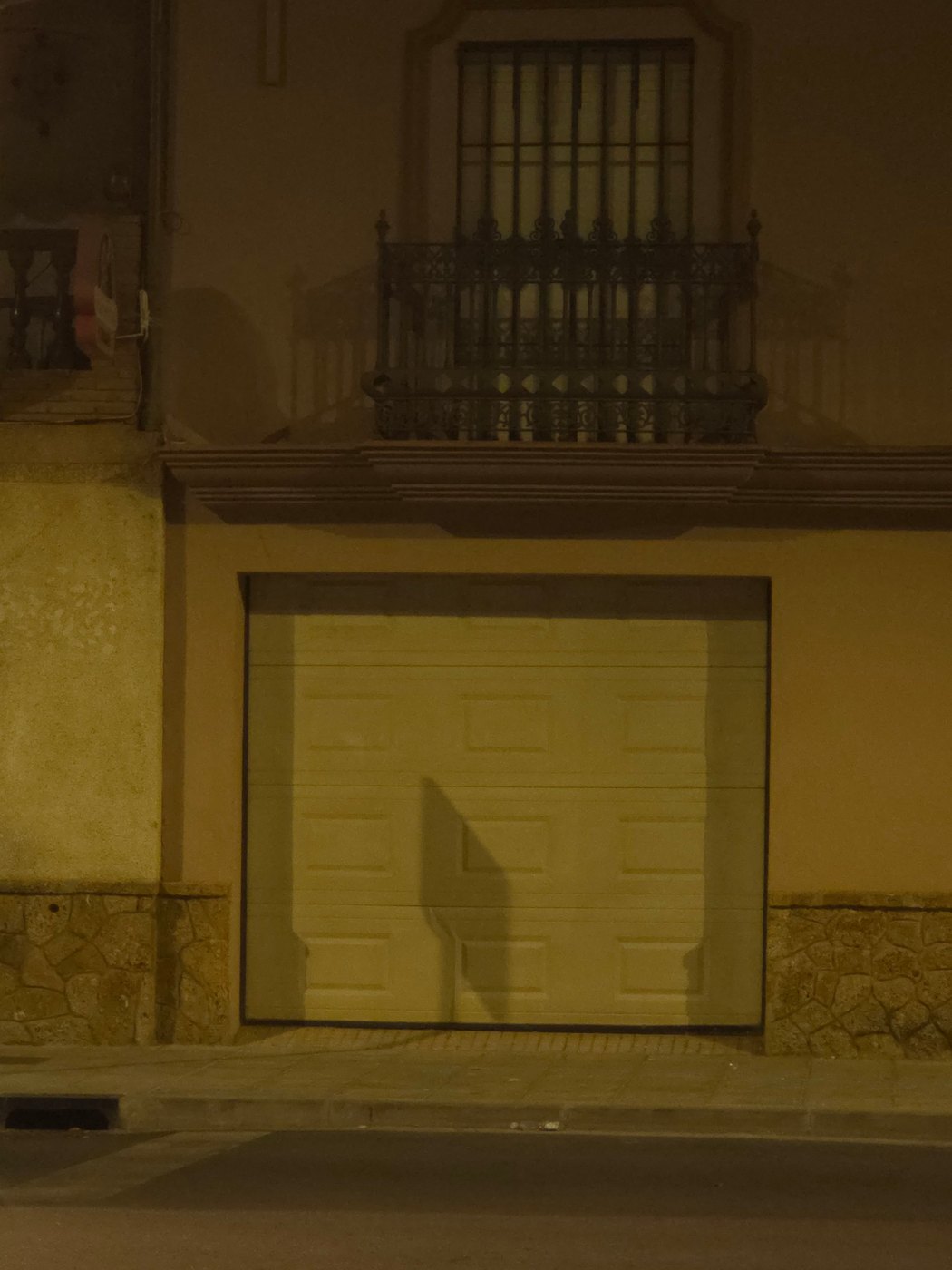 Garage door and balcony shadow under warm street light at night