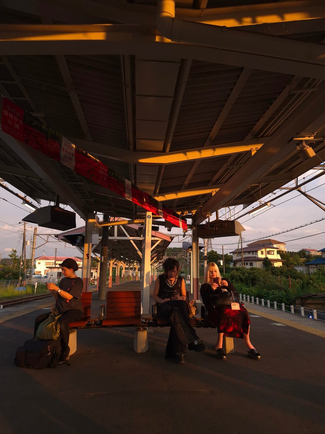 Train platform in Japan at golden hour, three people on benches