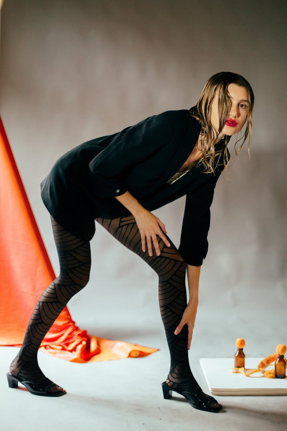 Model bending forward, orange fabric and small bottles